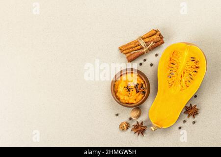 La moitié de la citrouille crue avec purée de courge musquée et épices. Assortiment d'ingrédients pour la cuisson, fond en béton de pierre, vue de dessus Banque D'Images