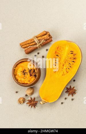 La moitié de la citrouille crue avec purée de courge musquée et épices. Assortiment d'ingrédients pour la cuisson, fond en béton de pierre, vue de dessus Banque D'Images