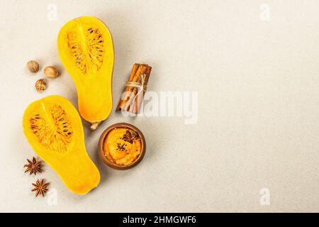 La moitié de la citrouille crue avec purée de courge musquée et épices. Assortiment d'ingrédients pour la cuisson, fond en béton de pierre, vue de dessus Banque D'Images