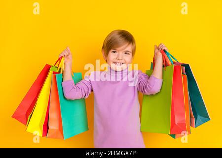 Photo de mignon adorable petit enfant petit garçon fils aller faire du shopping pour acheter maman cadeau pour anniversaire isolé sur fond jaune Banque D'Images