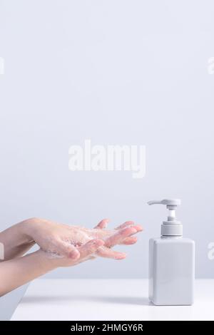 Se laver les mains à l'aide de savon liquide, concept d'hygiène pour protéger le coronavirus pandémique isolé sur fond gris blanc, gros plan. Banque D'Images