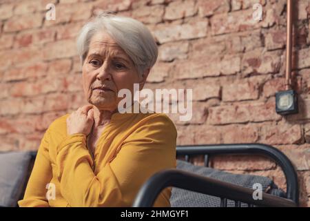 grand-mère solitaire déprimée assise seule sur un canapé. Photo de haute qualité Banque D'Images