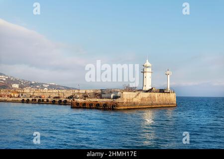 Vue panoramique sur l'ancien phare blanc sur la jetée en pierre du port de Yalta Crimean sur la mer Noire par une chaude journée ensoleillée. Balise nautique de la baie Banque D'Images