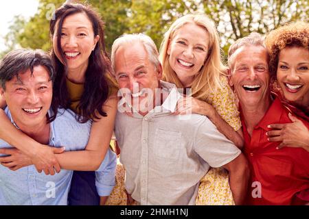 Groupe d'amis d'âge mûr à la surprise fête d'anniversaire pour femme dans le jardin avec gâteau et champagne Banque D'Images