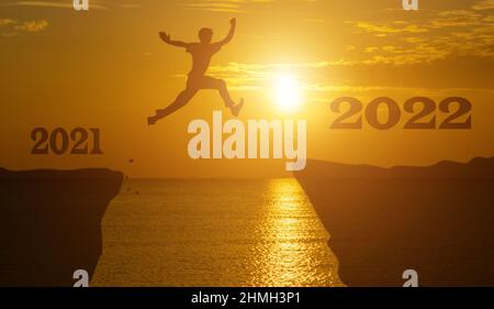 Silhouette homme saut entre 2021 et 2022 ans avec coucher de soleil, succès nouveau concept d'année. Banque D'Images