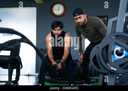 Entraîneur de gym d'enseignement corde exercice pour cardio - concept de l'entraînement de fitness, assistant entraîneur professionnel et culturisme Banque D'Images