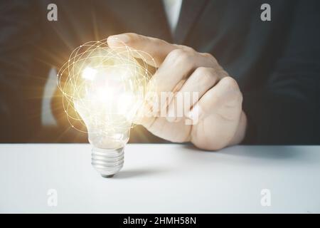 Homme d'affaires touchant une ampoule brillante. Concept d'idées pour présenter de nouvelles idées Grande inspiration et innovation Nouveau départ. Banque D'Images