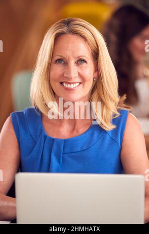 Portrait d'une femme d'affaires mûre avec ordinateur portable travaillant sur une table dans un café de bureau Banque D'Images