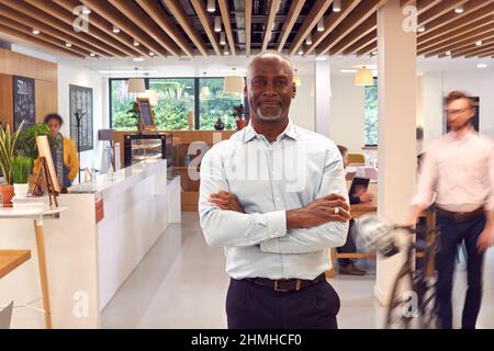 Portrait d'un homme d'affaires mûr debout dans un café de bureau très fréquenté Banque D'Images