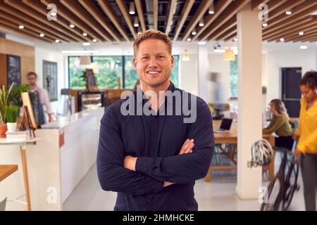 Portrait d'un homme d'affaires souriant debout dans un café de bureau très animé Banque D'Images