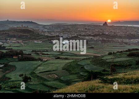 Le dernier jour de l'année, le soleil du matin se lève juste derrière la basilique de Goza, Malte, baignant le paysage en lumière dorée. Banque D'Images