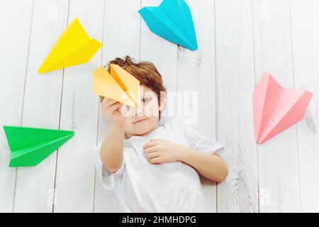 Heureux rire enfant jeter un avion de papier à l'intérieur. Bonne enfance, voyage, concept de vacances. Vue de dessus. Banque D'Images