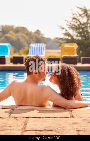 Vue arrière du couple romantique sur le point de Kiss dans la piscine en vacances Banque D'Images