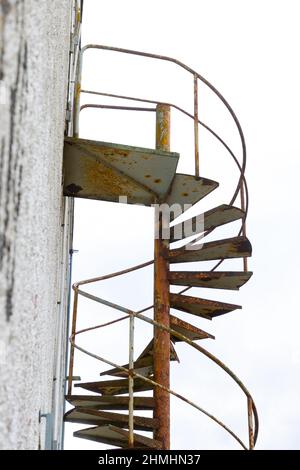 Vieux escalier en colimaçon rouillé menant à une porte fermée à l'extérieur d'un vieux bâtiment Banque D'Images