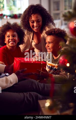 Échange familial et ouverture de cadeaux autour de l'arbre de Noël à la maison Banque D'Images