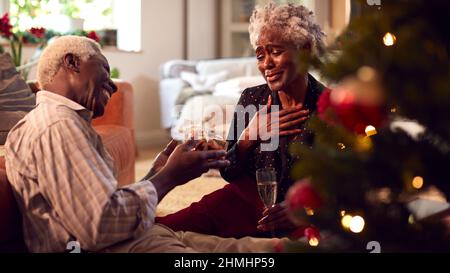 Amoureux couple Senior cadeaux d'ouverture autour de l'arbre de Noël à la maison Banque D'Images