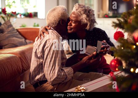 Amoureux couple Senior cadeaux d'ouverture autour de l'arbre de Noël à la maison Banque D'Images