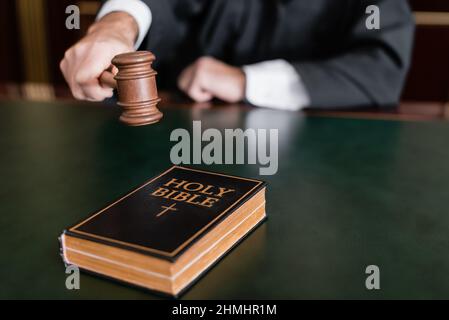 vue partielle d'un juge flou tenant le gavel près de la bible sainte sur le bureau Banque D'Images