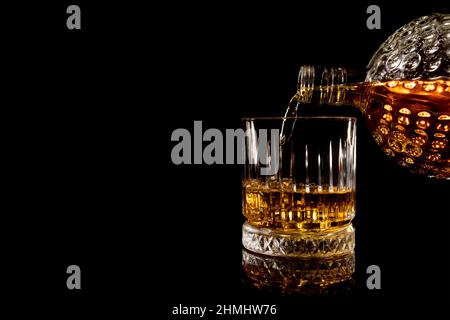 verser le verre de whisky sur fond noir Banque D'Images