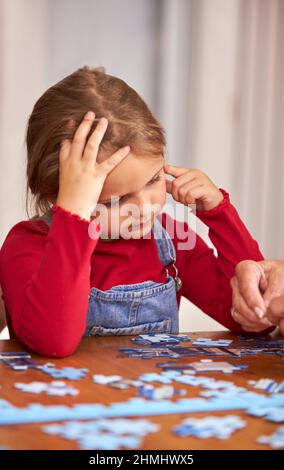 Gros plan de la petite-fille avec la grand-mère assis autour de la table à la maison faire le puzzle Jigsaw ensemble Banque D'Images