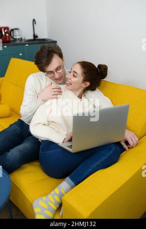 un jeune beau couple shopping en ligne. La fille se achète un cadeau. La femme est heureuse de l'achat Banque D'Images