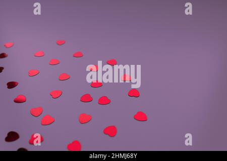 Coeurs rouges confettis sur fond violet de fête néon. Concept de l'amour, des rencontres et de la Saint-Valentin. Mise au point sélective, espace de copie Banque D'Images