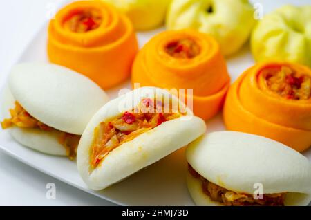 Petits pains Bao aux fruits de la viande cuits au barbecue, fruits de la viande cuits à la vapeur et légumes assaisonnés, enrobés d'une sauce barbecue et enveloppés d'un pain à la pâte, cuisine asiatique Banque D'Images