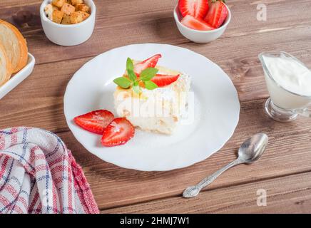Cocotte de fromage cottage à la crème fraîche et aux fraises sur une assiette blanche sur fond de bois sombre Banque D'Images