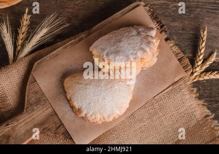 Délicieuse pâtisserie culinaire fraîche - petits pains sucrés farcis en poudre sucre sur fond de bois Banque D'Images