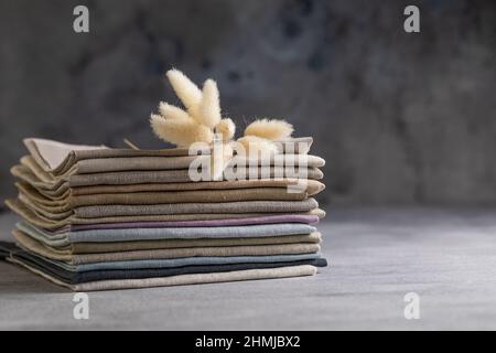 Un tas de quatre tissus en lin naturel aux couleurs ternes et pliés et respectueux de l'environnement sur fond gris Banque D'Images