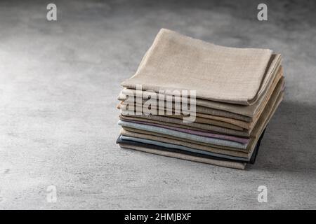 Un tas de quatre tissus en lin naturel aux couleurs ternes et pliés et respectueux de l'environnement sur fond gris Banque D'Images