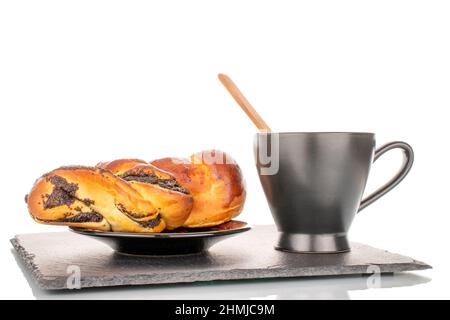 Un savoureux pain de graines de pavot maison avec soucoupe en céramique et tasse sur une pierre d'ardoise, macro, isolé sur un fond blanc. Banque D'Images