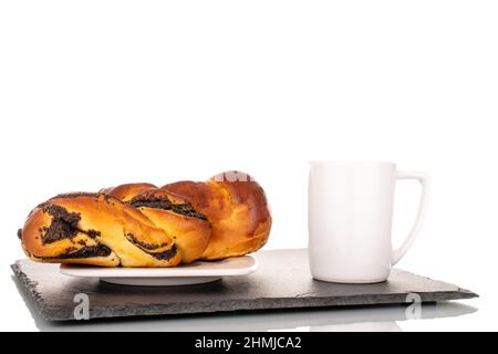 Un savoureux pain de graines de pavot maison avec soucoupe en céramique et tasse sur une pierre d'ardoise, macro, isolé sur un fond blanc. Banque D'Images