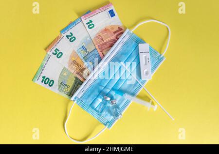 Argent (billets en euros) avec masques médicaux, test d'antigène, flacons de vaccins et seringue. Crise financière due aux pertes du coronavirus, sélectif f Banque D'Images