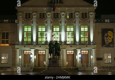 Weimar, Allemagne. 10th févr. 2022. Le foyer néoclassique situé au deuxième étage du Théâtre national allemand de Weimar est éclairé en vert derrière le monument Goethe et Schiller de Theaterplatz. Le 10 février, des campagnes ont été menées dans toute l'Allemagne pour attirer l'attention sur le travail des hospices pour enfants et pour recueillir des fonds. Le Théâtre national allemand de Weimar participe également à la campagne et sera symboliquement éclairé en vert pendant la soirée. Credit: Martin Schutt/dpa-Zentralbild/dpa/Alay Live News Banque D'Images