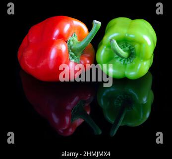 Pappers rouges et verts sur fond de studio réfléchissant noir Banque D'Images