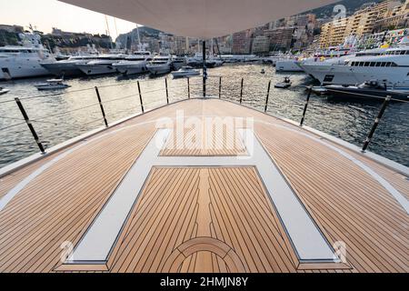 Le pont avant d'un énorme yacht dans le port de Monaco au coucher du soleil, le lieu d'atterrissage de l'hélicoptère, beaucoup de bateaux à moteur sont sur fond, le chrome Banque D'Images