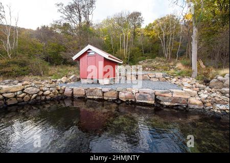 Lindesnes, Norvège - octobre 15 2011 : petit hangar en bois rouge près d'un port en pierre Banque D'Images