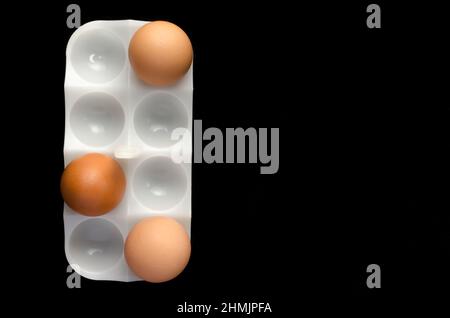 Trois oeufs de poule stand blanc sur fond noir,close up. Banque D'Images