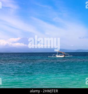 Volcan actif du mont Agung, couvert de nuages à Nusa Penida, île de Bali, Indonésie. Des bateaux de pêche traditionnels appelés jukung sur la plage de sable blanc. Banque D'Images