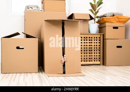 Un petit garçon excité se cachant dans une énorme boîte en carton. Il joue et regarde hors d'une boîte. Un enfant est heureux de s'installer dans une nouvelle maison. Banque D'Images