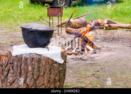 Pique-nique avec feu. La hache et le pot sont sur le quai près du feu pendant le pique-nique sur le lac. Banque D'Images