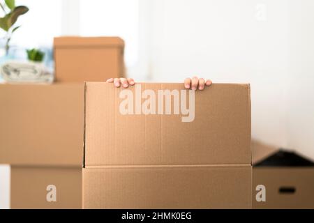 Un petit garçon excité se cachant dans une énorme boîte en carton. Il joue et va sauter hors de la boîte. Un enfant est heureux de s'installer dans une nouvelle maison. Banque D'Images