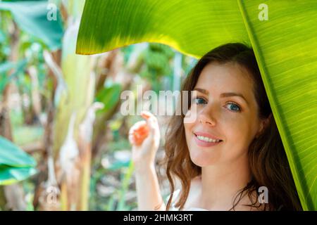 Beau jeune caucasien brunette femme portrait près de la banane palmier laisse des plantes tropicales dans la jungle. Soins de la peau et beauté naturelle organique, personnel Banque D'Images