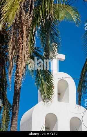 Crête blanche d'une église chrétienne moderne contre le ciel bleu et les feuilles de palmier tout autour. Playa del Carmen, Mexique Banque D'Images