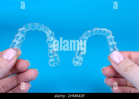 Supports invisibles transparents renforts invisalign. Mains caucasiennes femelles tenant deux aligneurs ou retenues en plastique Banque D'Images