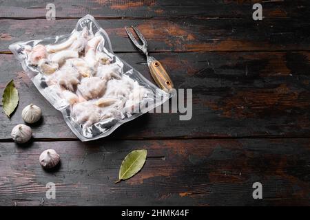 Ensemble de fruits de mer surgelés, anneaux de calmars, set de crevettes et poulpe sous vide, sur fond de table en bois foncé, avec espace pour le texte Banque D'Images