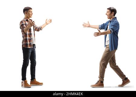 Photo de profil pleine longueur de deux jeunes hommes marchant l'un vers l'autre avec des bras larges ouverts isolés sur fond blanc Banque D'Images