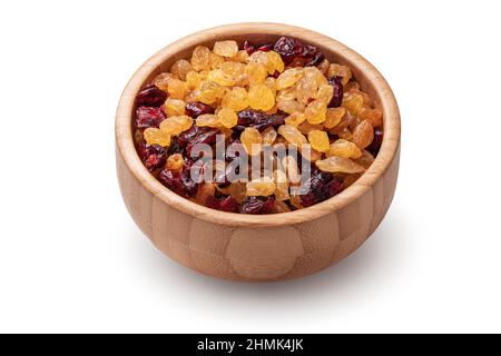 Raisins secs et canneberges biologiques dans un bol en bois isolé sur fond blanc. Banque D'Images
