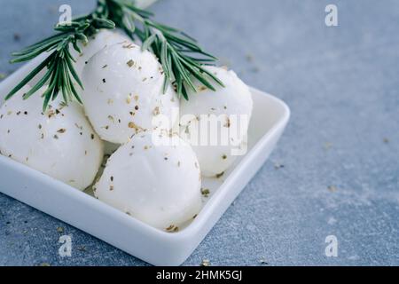 Fromage blanc italien frais mozzarella buffle dans un bol blanc servi avec une branche de romarin frais Banque D'Images